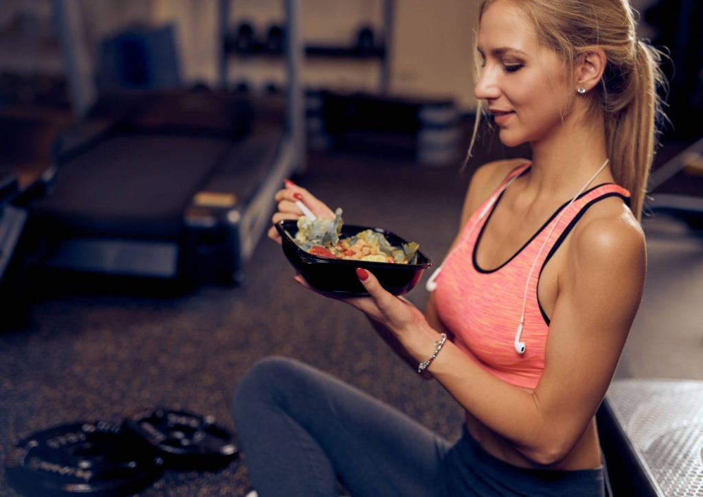 En dame spiser et måltid med proteiner og karbohydrater etter trening